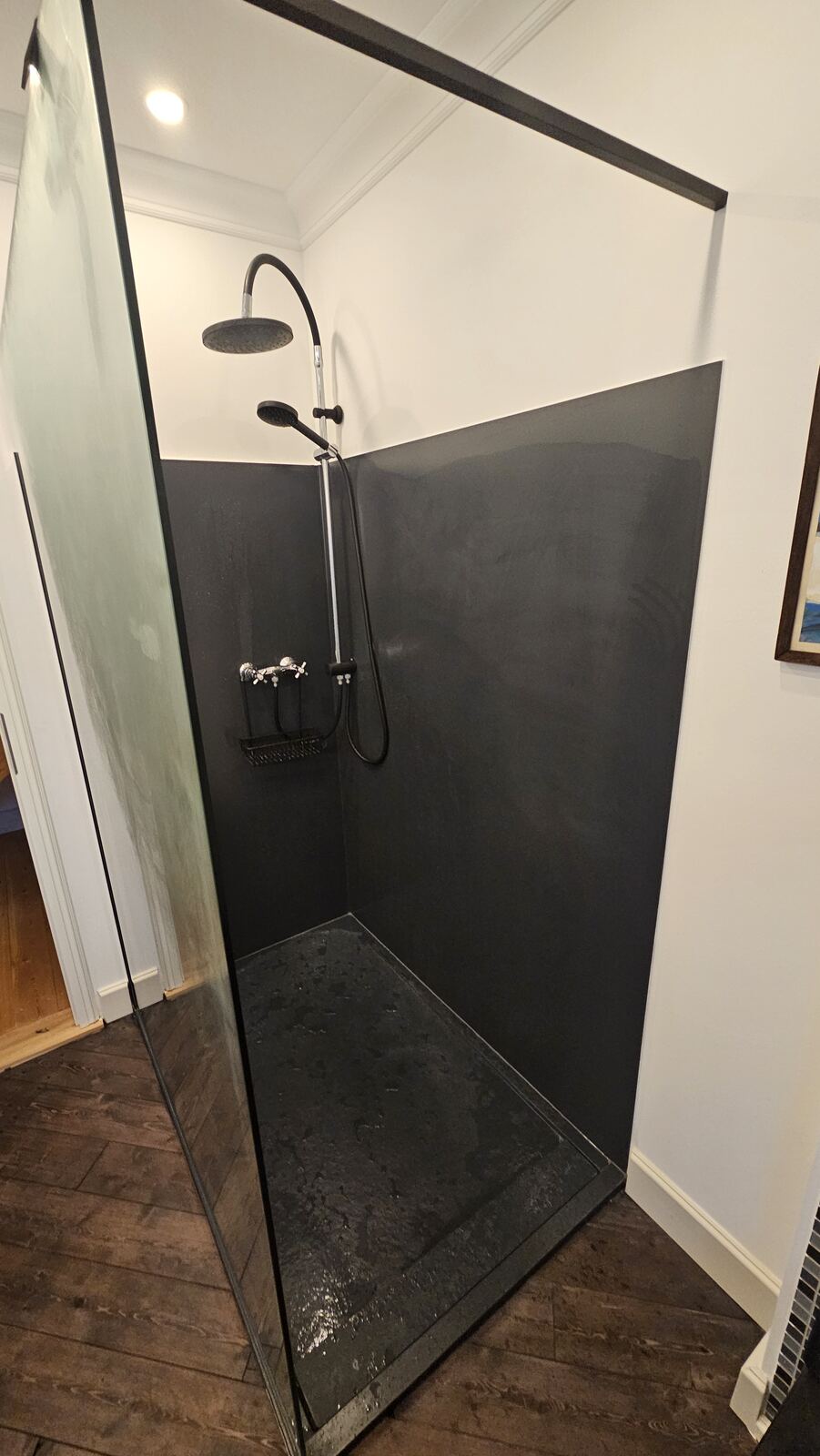 Bodengleiche Dusche mit dunkler Wand und Glasabtrennung unter einer Dachschräge