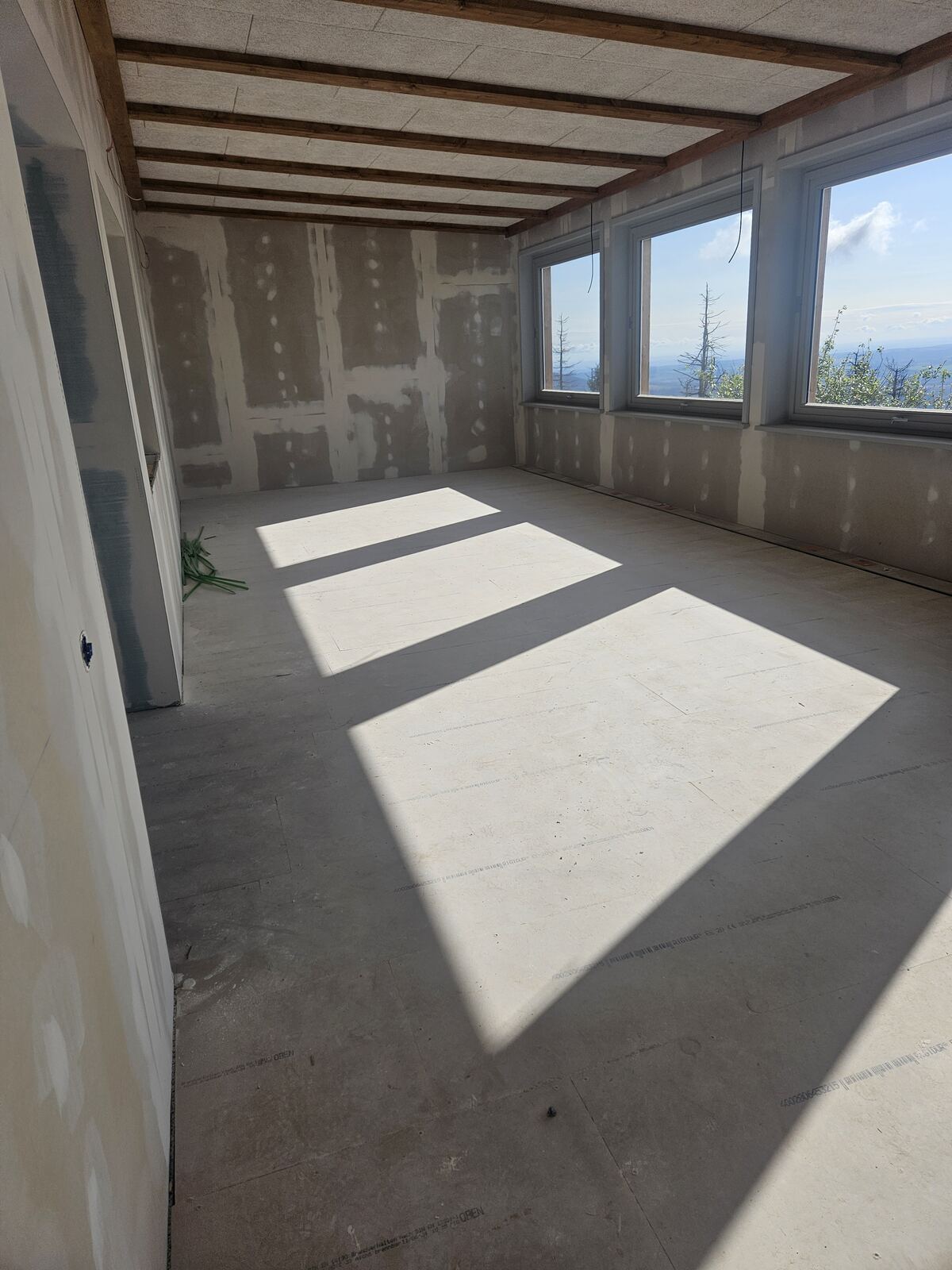 Offenes Dachgeschoss im Ausbau, Sonnenlicht fällt durch eine Fensterreihe