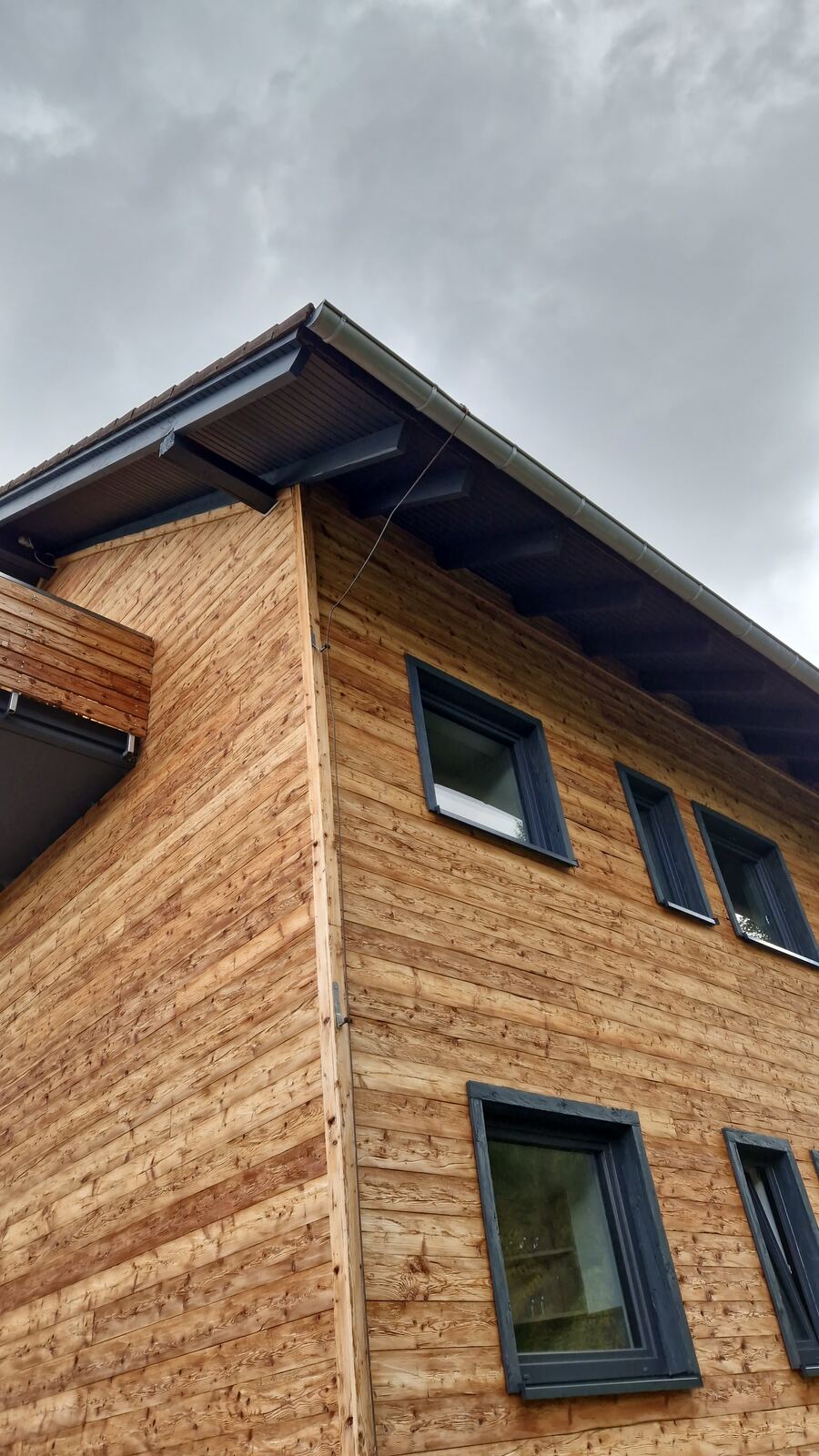 Giebel eines Hauses mit neuer Holzschalung und dunklen Fenstern